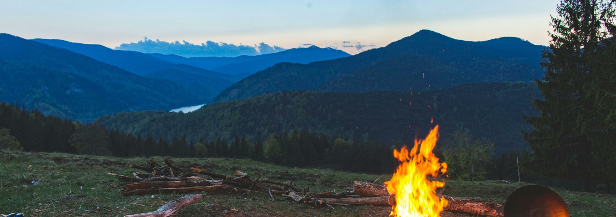 A mountain landscape with a bonfire at the front.